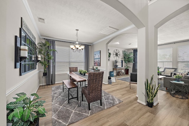 15026 Grape Orchard Ct, Cypress, TX 77433 - dining space with ornamental molding, light wood-style floors, a chandelier, a textured ceiling, and arched walkways