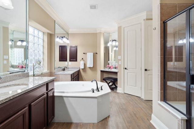 10522 Ginger Gln, Missouri City, TX 77459 - bathroom featuring a stall shower, two vanities, wood finished floors, a bath, and ornamental molding