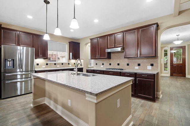 10522 Ginger Gln, Missouri City, TX 77459 - kitchen featuring appliances with stainless steel finishes, arched walkways, light wood-type flooring, a kitchen island with sink, and recessed lighting