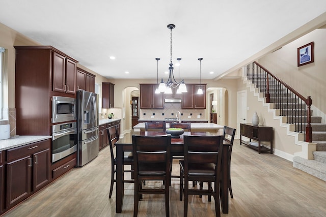 10522 Ginger Gln, Missouri City, TX 77459 - dining space featuring arched walkways, light wood-style floors, stairway, and recessed lighting