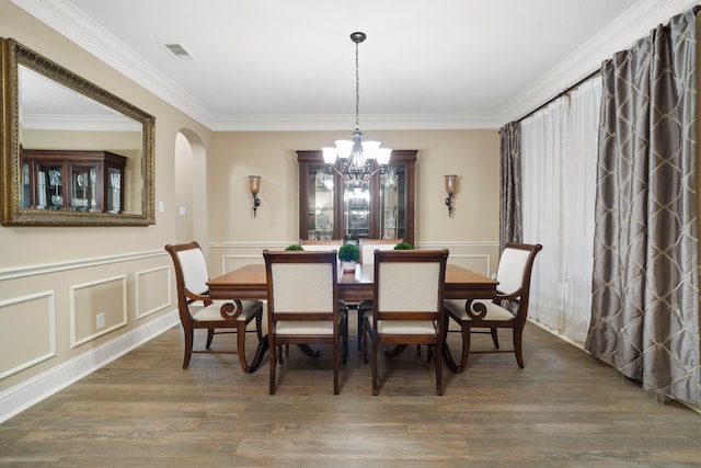 10522 Ginger Gln, Missouri City, TX 77459 - dining area with ornamental molding, a chandelier, wood finished floors, arched walkways, and wainscoting