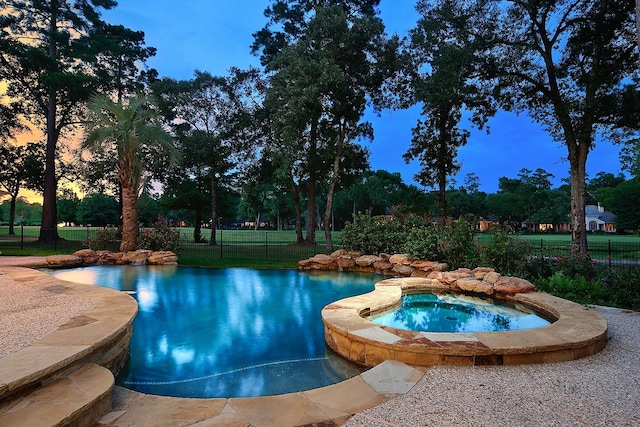 303 S Silvershire Cir, The Woodlands, TX 77381 - pool at dusk featuring a pool with connected hot tub