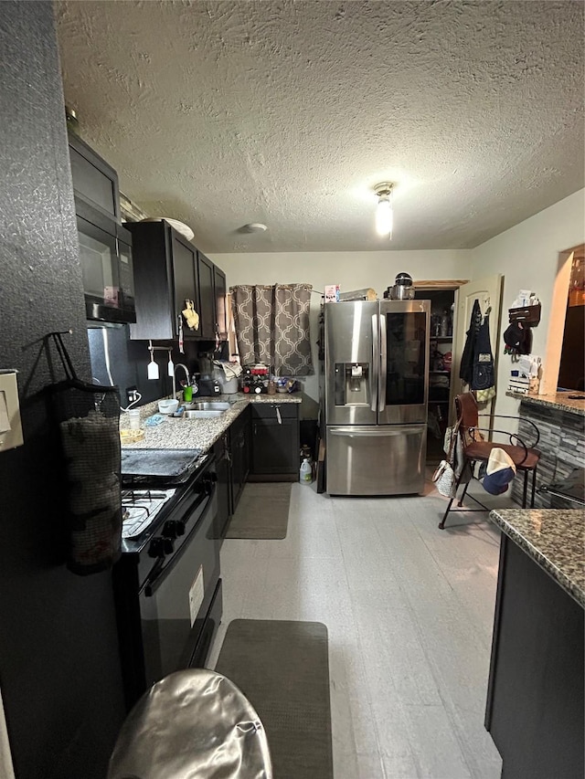 1114 Elton St, Houston, TX 77034 - kitchen with stainless steel refrigerator with ice dispenser, black gas range oven, dark cabinets, a textured ceiling, and light stone countertops