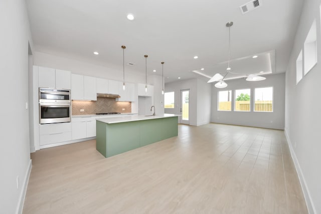 3003A Ventas Dr, Houston, TX 77047 - kitchen featuring stainless steel double oven, white cabinetry, a kitchen island with sink, decorative backsplash, and recessed lighting