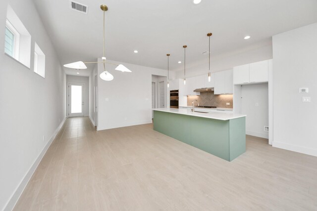 3003A Ventas Dr, Houston, TX 77047 - kitchen with recessed lighting, white cabinets, backsplash, light countertops, and an island with sink