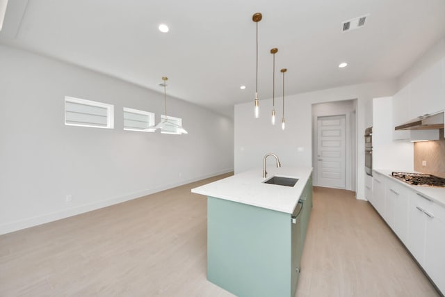 3003A Ventas Dr, Houston, TX 77047 - kitchen with appliances with stainless steel finishes, white cabinets, light wood-style floors, light countertops, and under cabinet range hood
