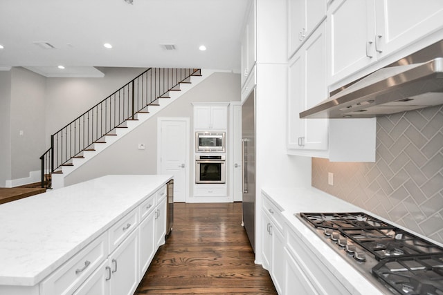 206 Green Blvd, Shenandoah, TX 77384 - kitchen with under cabinet range hood, built in appliances, tasteful backsplash, dark wood finished floors, and white cabinetry