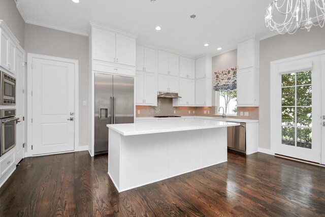 206 Green Blvd, Shenandoah, TX 77384 - kitchen with built in appliances, under cabinet range hood, light countertops, dark wood-style flooring, and crown molding