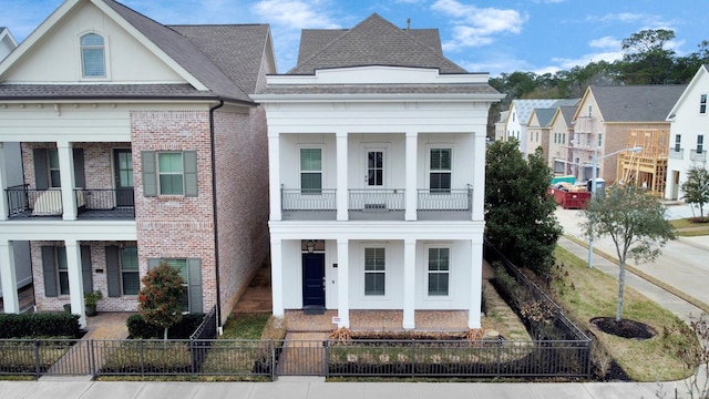 206 Green Blvd, Shenandoah, TX 77384 - view of front of house with a porch, a balcony, brick siding, a fenced front yard, and roof with shingles
