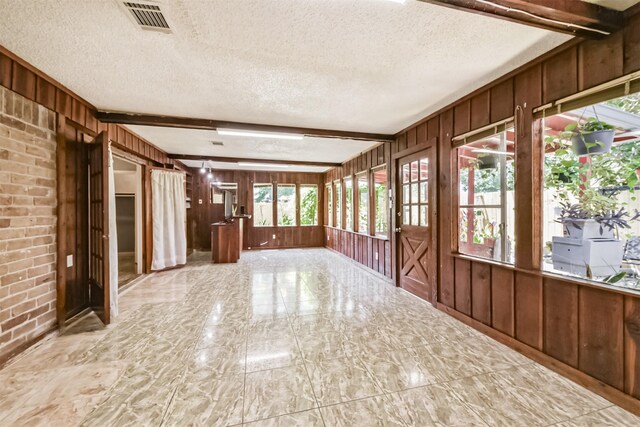10806 Sagegulf Ln, Houston, TX 77089 - unfurnished sunroom with wood walls, plenty of natural light, marble finish floors, a textured ceiling, and beamed ceiling