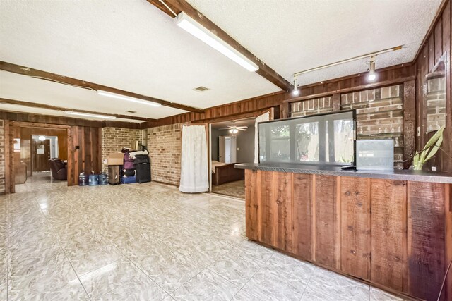 10806 Sagegulf Ln, Houston, TX 77089 - kitchen featuring wooden walls, brick wall, beam ceiling, dark countertops, and ceiling fan
