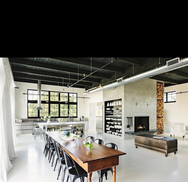 2520 Houston Ave Unit 701, Houston, TX 77009 - dining room featuring concrete flooring, healthy amount of natural light, a towering ceiling, and a large fireplace