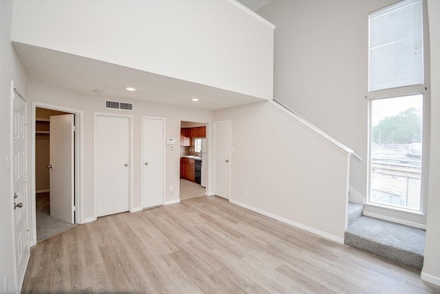 10855 Meadowglen Ln Unit 721, Houston, TX 77042 - unfurnished living room with plenty of natural light, stairway, light wood finished floors, a towering ceiling, and recessed lighting