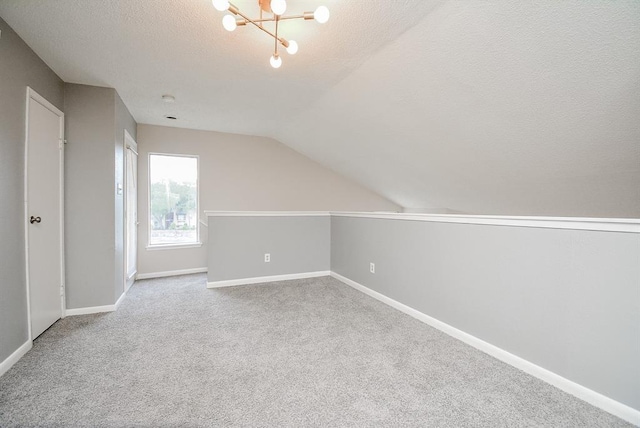 10855 Meadowglen Ln Unit 721, Houston, TX 77042 - bonus room with a textured ceiling, vaulted ceiling, carpet, and a chandelier