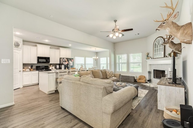 2337 Shalmar Dr, West Columbia, TX 77486 - living room with light wood finished floors, a ceiling fan, a tile fireplace, a chandelier, and recessed lighting