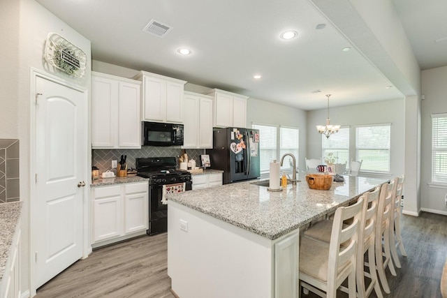 2337 Shalmar Dr, West Columbia, TX 77486 - kitchen featuring black appliances, backsplash, white cabinetry, a center island with sink, and recessed lighting
