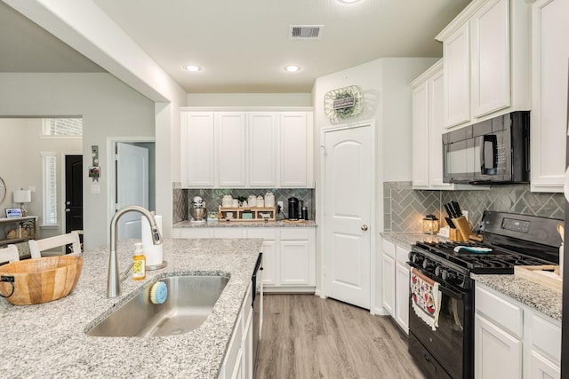 2337 Shalmar Dr, West Columbia, TX 77486 - kitchen with black appliances, white cabinets, light wood finished floors, decorative backsplash, and light stone counters