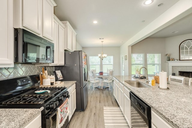 2337 Shalmar Dr, West Columbia, TX 77486 - kitchen with black appliances, white cabinets, a chandelier, light wood-style floors, and light stone counters