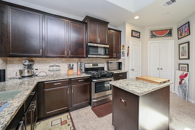 12207 Green City Ln, Houston, TX 77047 - kitchen with appliances with stainless steel finishes, decorative backsplash, light tile patterned floors, light stone counters, and recessed lighting