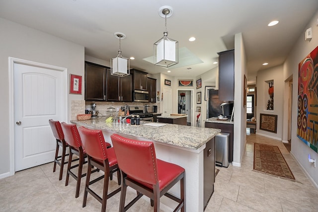 12207 Green City Ln, Houston, TX 77047 - kitchen with stainless steel appliances, tasteful backsplash, dark brown cabinetry, a peninsula, and a breakfast bar