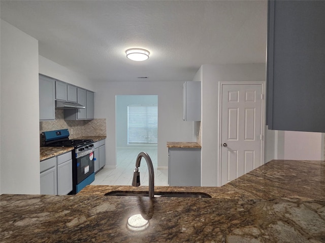 2703 Oakland Brook St, Houston, TX 77038 - kitchen featuring gas stove, under cabinet range hood, gray cabinets, and dark stone counters