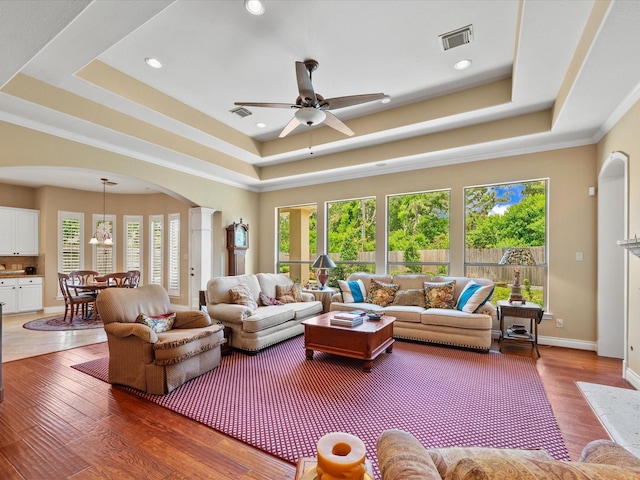 6922 Carolina Cherry Ln, Spring, TX 77389 - living room with a tray ceiling, a ceiling fan, decorative columns, arched walkways, and wood finished floors