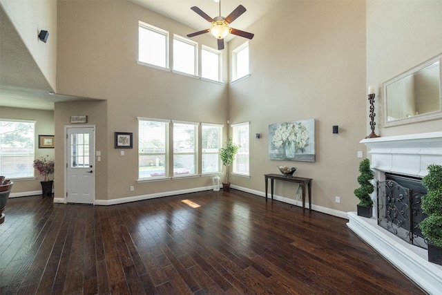27619 Dalton Bluff Ct, Katy, TX 77494 - unfurnished living room featuring a ceiling fan, a towering ceiling, a fireplace with raised hearth, and dark wood finished floors