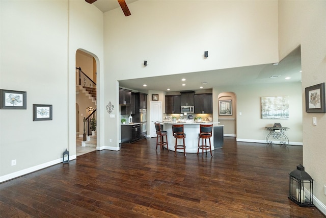 27619 Dalton Bluff Ct, Katy, TX 77494 - kitchen featuring arched walkways, a towering ceiling, light countertops, appliances with stainless steel finishes, and dark wood-style flooring