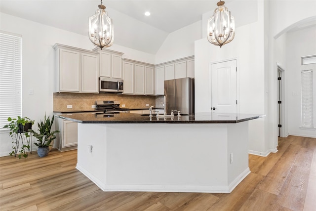 9427 Harmony Lake Ln, Richmond, TX 77469 - kitchen with appliances with stainless steel finishes, a chandelier, backsplash, a center island with sink, and high vaulted ceiling