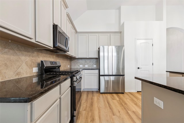 9427 Harmony Lake Ln, Richmond, TX 77469 - kitchen featuring stainless steel appliances, light wood-style flooring, backsplash, dark stone counters, and lofted ceiling