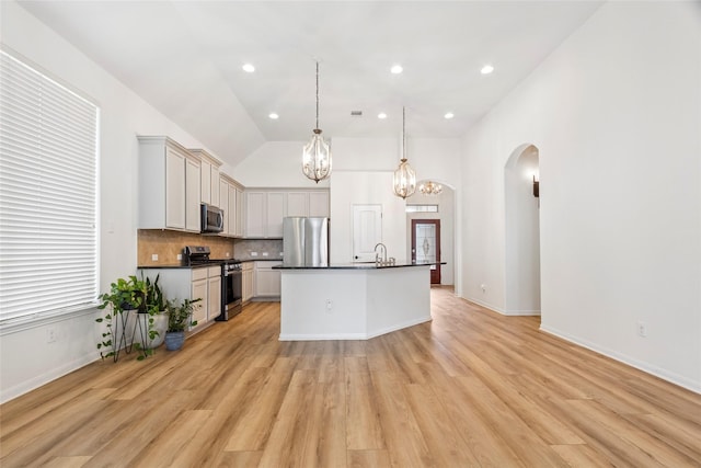 9427 Harmony Lake Ln, Richmond, TX 77469 - kitchen featuring stainless steel appliances, dark countertops, arched walkways, a chandelier, and tasteful backsplash