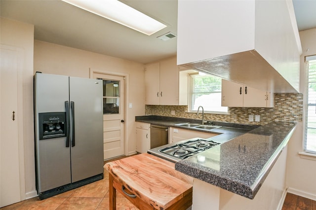 4502 Sanford Rd, Houston, TX 77035 - kitchen featuring stainless steel appliances, dark countertops, range hood, tasteful backsplash, and a peninsula
