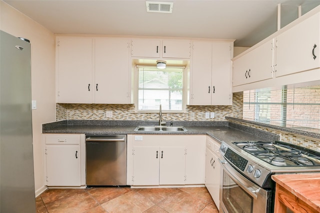 4502 Sanford Rd, Houston, TX 77035 - kitchen with appliances with stainless steel finishes, backsplash, dark countertops, and white cabinets