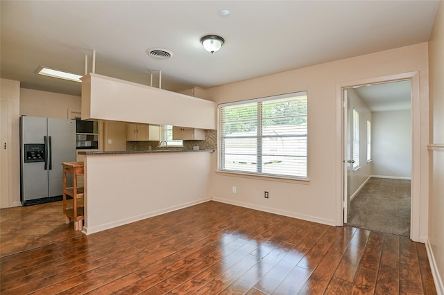 4502 Sanford Rd, Houston, TX 77035 - kitchen featuring stainless steel refrigerator with ice dispenser, dark countertops, dark wood-style flooring, a peninsula, and tasteful backsplash