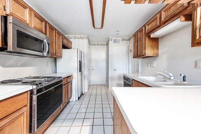 16160 Seahorse Dr, Houston, TX 77062 - kitchen with stainless steel appliances, light tile patterned floors, light countertops, and brown cabinetry