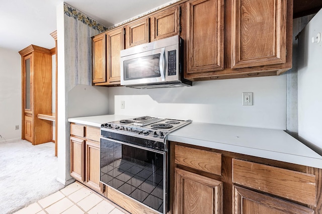 16160 Seahorse Dr, Houston, TX 77062 - kitchen with electric stove, stainless steel microwave, light countertops, brown cabinets, and light colored carpet