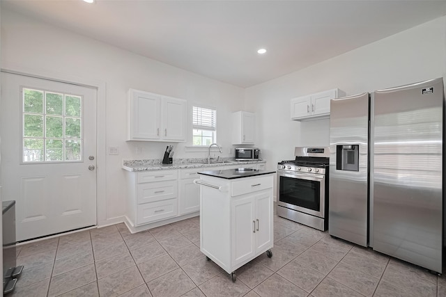 4401 Canal St, Houston, TX 77011 - kitchen with stainless steel appliances, white cabinetry, light tile patterned floors, a center island, and recessed lighting