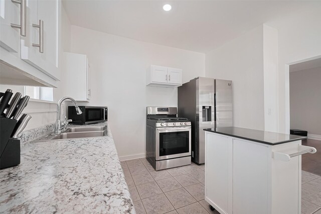 4401 Canal St, Houston, TX 77011 - kitchen featuring appliances with stainless steel finishes, white cabinets, light tile patterned flooring, a kitchen island, and recessed lighting