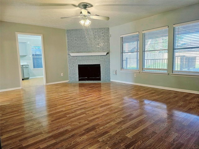 7715 Lobera Dr, Houston, TX 77083 - unfurnished living room with ceiling fan, wood finished floors, a textured ceiling, and a brick fireplace