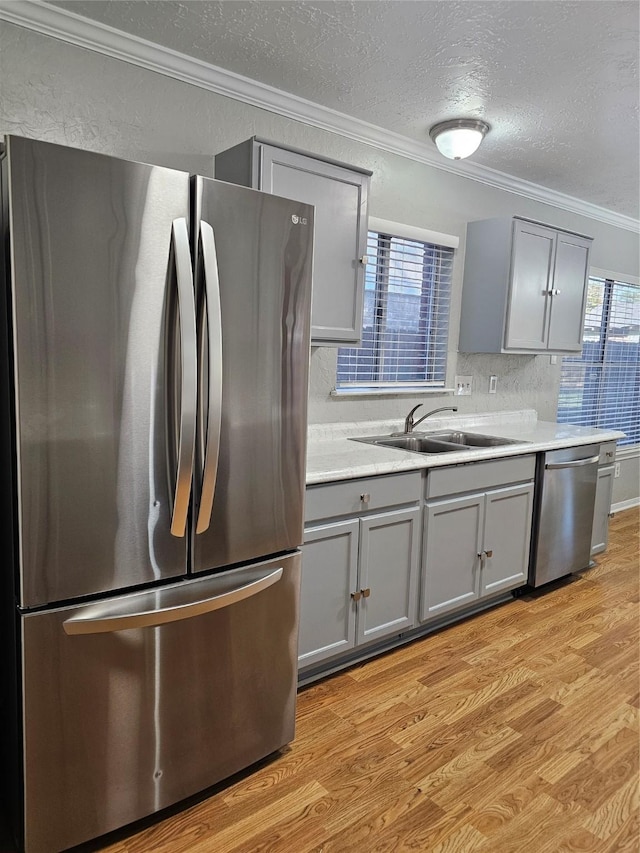 7715 Lobera Dr, Houston, TX 77083 - kitchen featuring appliances with stainless steel finishes, gray cabinetry, ornamental molding, light wood finished floors, and light countertops