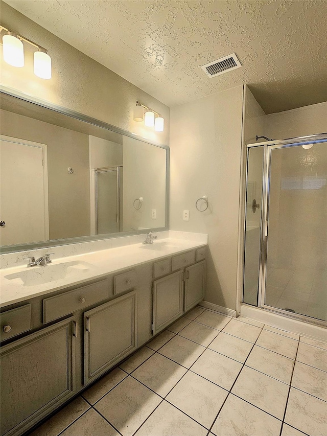7715 Lobera Dr, Houston, TX 77083 - bathroom featuring a textured ceiling, tile patterned flooring, double vanity, and a stall shower