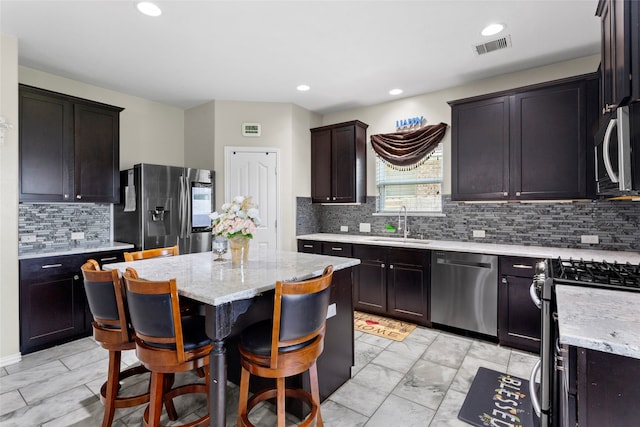 6605 Fallen Breeze Ln, Dickinson, TX 77539 - kitchen with appliances with stainless steel finishes, light marble finish flooring, light stone countertops, tasteful backsplash, and a center island