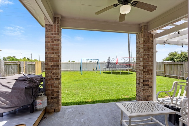 6605 Fallen Breeze Ln, Dickinson, TX 77539 - fenced backyard with a patio area, a ceiling fan, area for grilling, a trampoline, and a playground