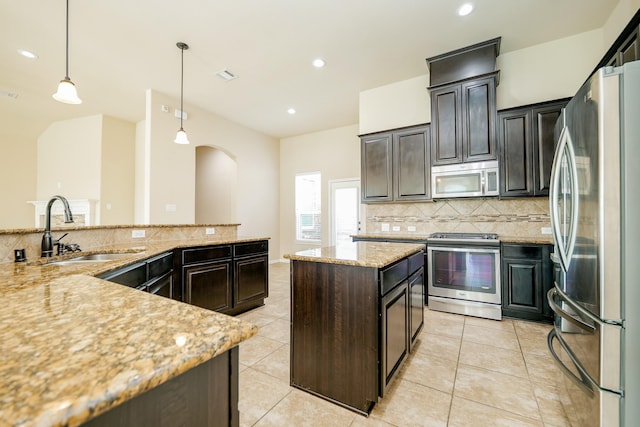 9335 Mystic Falls Ln, Humble, TX 77396 - kitchen featuring appliances with stainless steel finishes, backsplash, a spacious island, decorative light fixtures, and light stone countertops