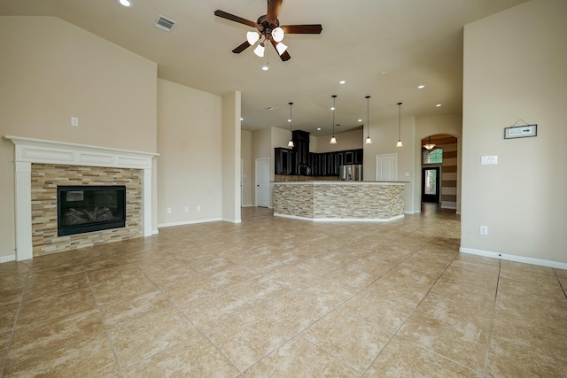 9335 Mystic Falls Ln, Humble, TX 77396 - unfurnished living room featuring a ceiling fan, a high ceiling, recessed lighting, arched walkways, and a tile fireplace