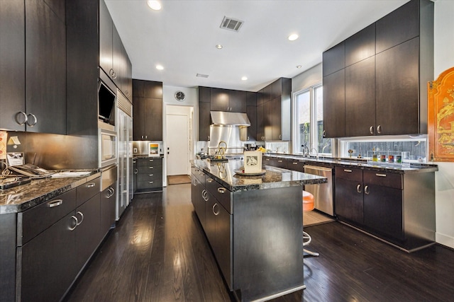2409 Maconda Ln, Houston, TX 77027 - kitchen featuring stainless steel dishwasher, under cabinet range hood, dark wood-type flooring, a kitchen island, and recessed lighting