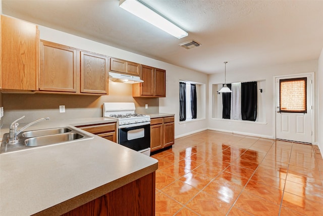 14006 Marners Ct, Houston, TX 77014 - kitchen featuring white gas stove, under cabinet range hood, light countertops, light tile patterned flooring, and hanging light fixtures