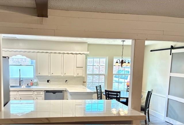 29019 Elmwood Dr, Shenandoah, TX 77381 - kitchen featuring dishwasher, white cabinets, healthy amount of natural light, light countertops, and a textured ceiling