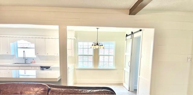 29019 Elmwood Dr, Shenandoah, TX 77381 - kitchen with white cabinetry, beamed ceiling, a barn door, a chandelier, and light countertops