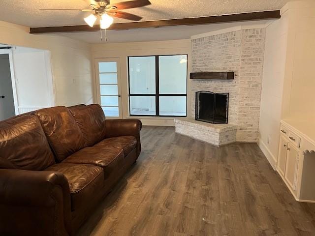 29019 Elmwood Dr, Shenandoah, TX 77381 - living area featuring a textured ceiling, beam ceiling, a ceiling fan, dark wood-type flooring, and a fireplace